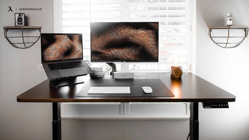 Clean minimalist desk setup with wireless peripherals, monitor, and organized cable management in a small space
