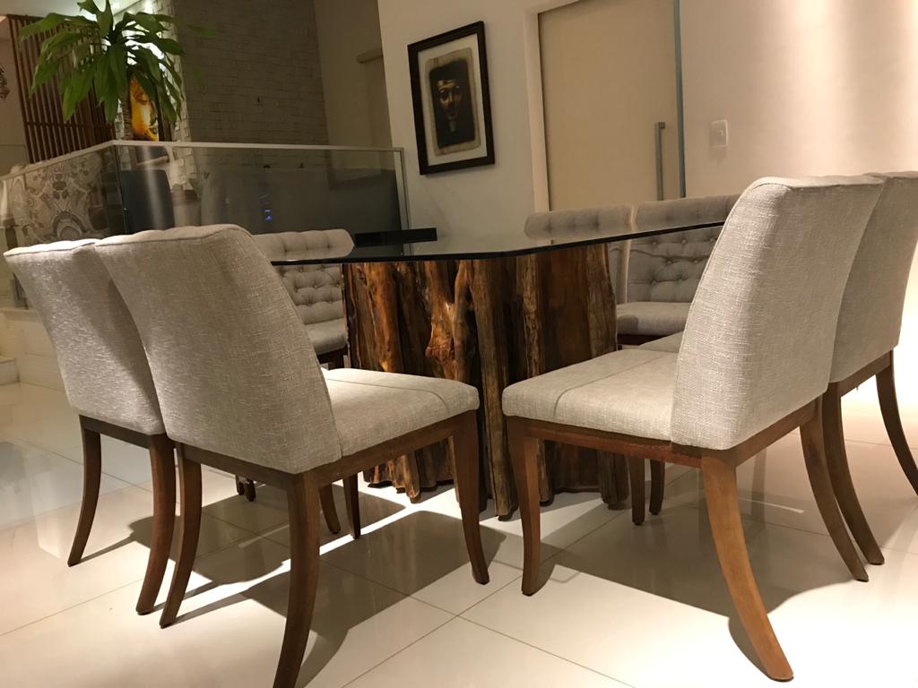 Mesa de jantar retangular de madeira maciça com tampo de vidro e cadeiras estofadas em ambiente elegante