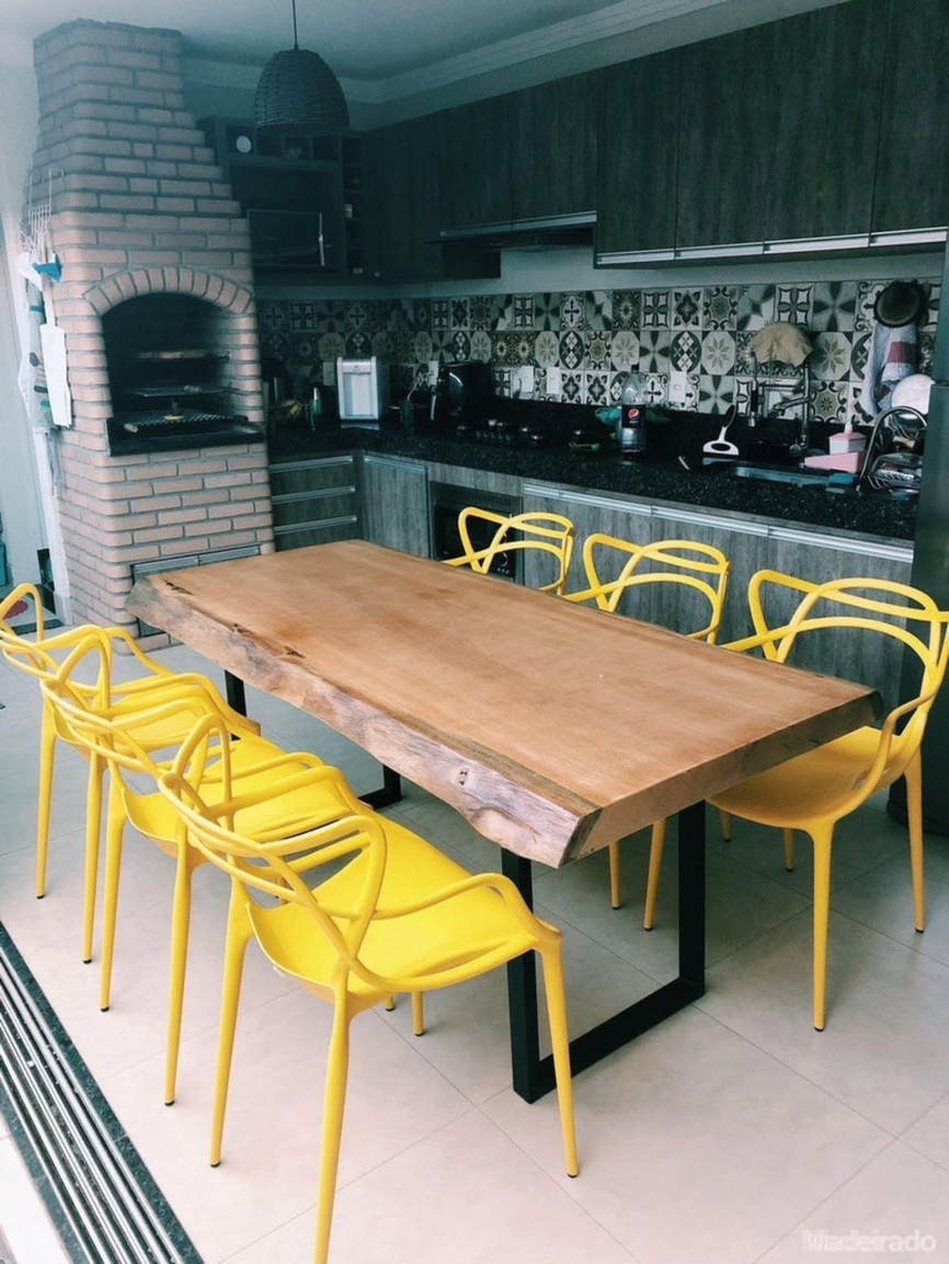 Mesa de jantar de madeira maciça com cadeiras amarelas em ambiente integrado